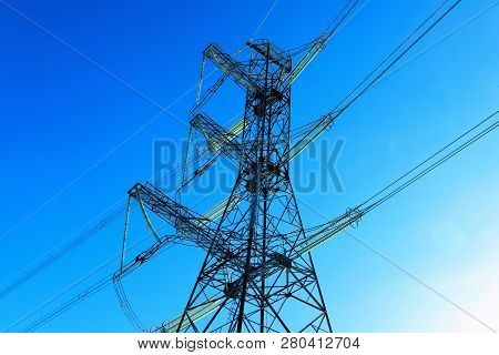 A Transmission Tower Or Electricity Pylon With Blue Sky. It Is A Tall Structure, Usually A Steel Lat
