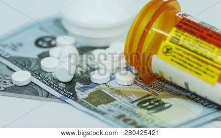 A Prescription Bottle Lying On Its Side With Oxycodone Pills Spilling Out Onto One Hundred Dollor Bi