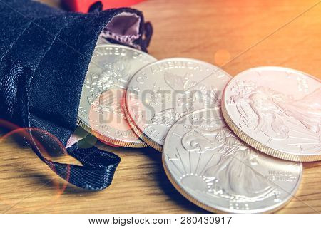 Closeup Of Silver Coins American One Ounce Eagles And Brick Falling Out Of Black Money Bag And Layin