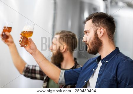 alcohol production, manufacture, business and people concept - men drinking and testing craft beer at brewery