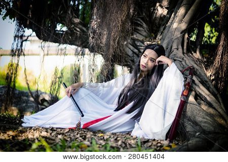Beautiful Chinese Woman With A Traditional Suit With A Flute In Her Hands, Beautiful And Belligerent