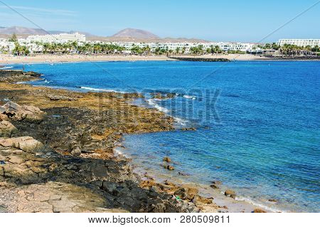 Golden Sand And Volcanic Rocks At Las Cucharas Beach, Lanzarote, Canary Islands. View Of The Sea, Co