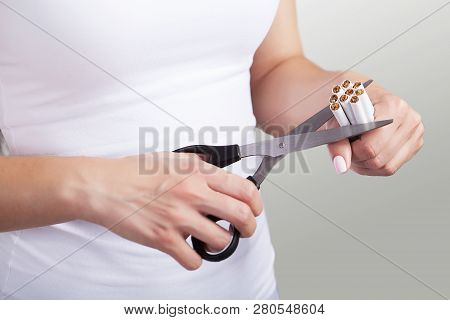 Quit Smoking. Closeup Of Womens Hands Holding A Bunch Of Cigarettes And Cutting Them In Half Scissor