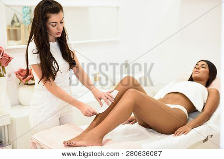 Woman Having Hair Removal Procedure On Leg Applying Wax Strip