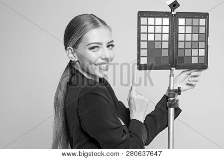 Young Photographer Pointing At Color Checker Card, While Working In Studio. Girl In Formal Suit Prep