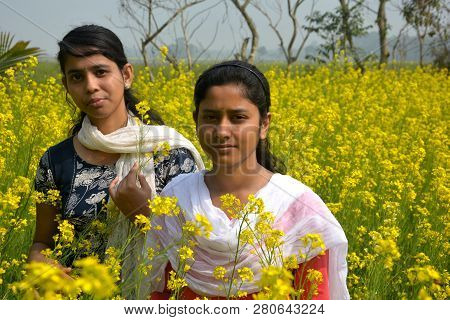 Two Beautiful Asian Teens Standing In A Mustard, Rape Field With Yellow Color Flowers, Covering Head