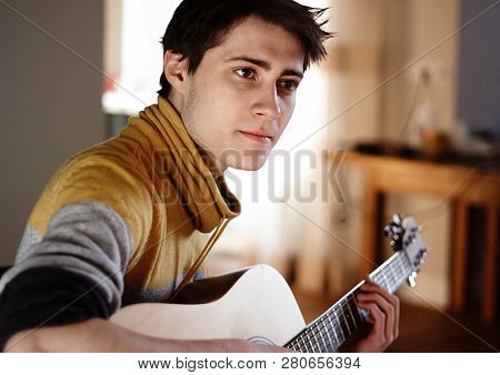 Guy In Yellow Sweater Plays Acoustic Guitar While Sitting At Home