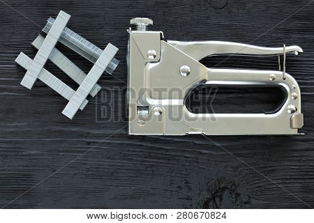 Metal Industrial Chrome Stapler Gun And Staples To It On A Black Background