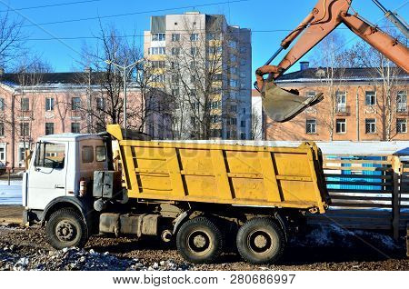The Excavator Loads Crushed Stone In A Dump Truck Body. Iron Bucket Digging Machine.