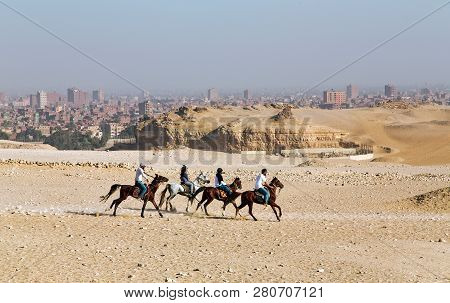 Egypt, Cairo, November, 2017 - Three Egyptian Men And One Woman Ride Horses To The Pyramids On The G