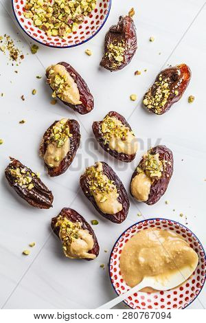 Dates Stuffed With Peanut Butter And Pistachios On A White Background. Healthy Vegan Food Concept.