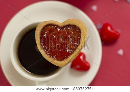 Close Up Heart Shape Cookie With Strawberry Jam. Cup Of Coffee, Morning Drink. Red Background.