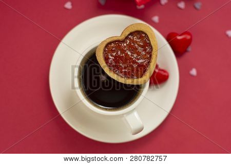 Close Up Heart Shape Cookie With Strawberry Jam. Cup Of Coffee, Morning Drink. Red Background.