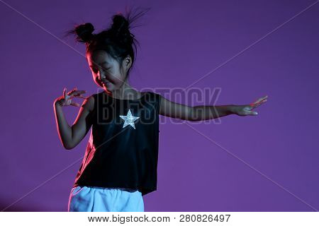 Joyfull Asian Kid Girl In Shirt And Pants With Stars And On Purple Background Dance
