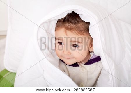 Portrait Of Baby Girl Lying In Bed Under Featherbed