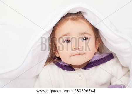 Portrait Of Baby Girl Lying In Bed Under Featherbed