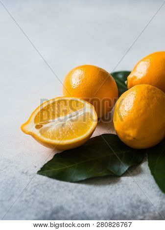 Orange Meyeri Lemons With Green Leaves In A Group On A Gray Background.