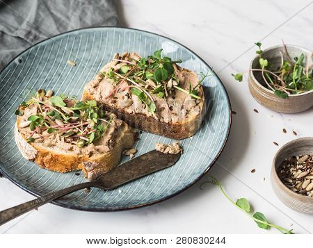 Two Toasts Duck With Prunes Rillettes Pate On White Bread With Sprouts And Various Seeds On A Blue P