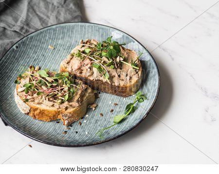 Two Toasts Duck With Prunes Rillettes Pate On White Bread With Sprouts And Various Seeds On A Blue P