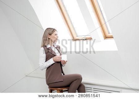 Blonde Girl In A Business Suit Works On A Computer In A White Bright Office.