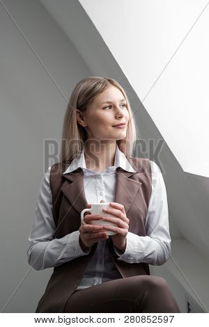 Blonde Girl In A Business Suit Works On A Computer In A White Bright Office.