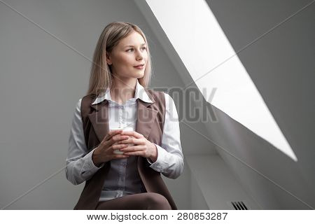 Blonde Girl In A Business Suit Works On A Computer In A White Bright Office.
