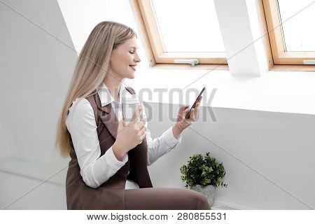 Blonde Girl In A Business Suit Works On A Computer In A White Bright Office.