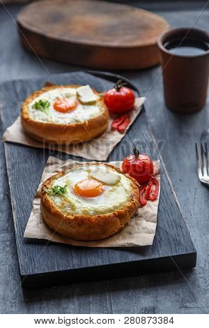 Bread With Cheese And Yolk For Breakfast On Black Cutting Board