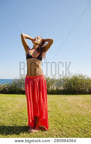 Sensual Girl On Sea Beach. Eastern Beauty. Summer Vacation And Travel. Suntan. Woman Dancing With Se