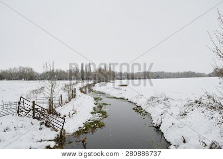 Scenic View Of A River In A Snow Covered Field