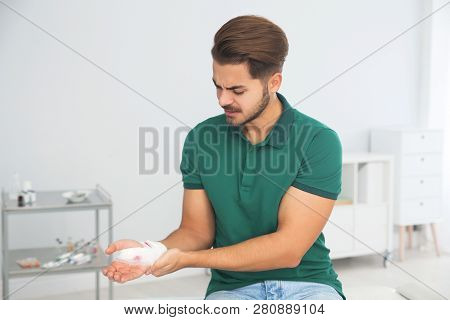 Young Man With Bandage On Injured Hand In Clinic. First Aid