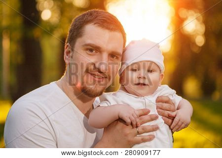 Baby with faher in the park in the rays of sunset. Toddler on the nature outdoors. Backlight. Summertime family  scene