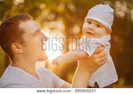 Baby with faher in the park in the rays of sunset. Toddler on the nature outdoors. Backlight. Summertime family  scene
