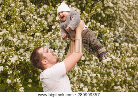 Baby with faher in the park in the rays of sunset. Toddler on the nature outdoors. Backlight. Summertime family  scene