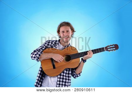 Young Man Playing Acoustic Guitar On Color Background