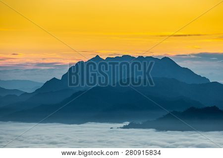 Big Blue Mountain Covered By Fog With Yellow Warm Sunrise Sky Of Doi Luang Chiangdao, Chiangmai, Tha