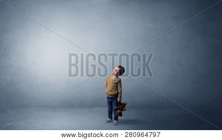 Little waggish kid staying alone in a big empty room with his plush