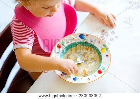Close-up Baby Girl Eating From Spoon Vegetable Noodle Soup. Food, Child, Feeding And Development Con