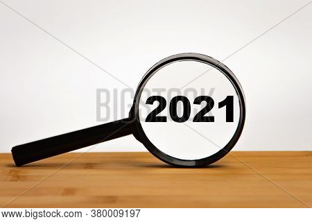 Focused On Business Concept. Magnifier Glass With Word Numbers 2021 On Wooden Table. Business Concep