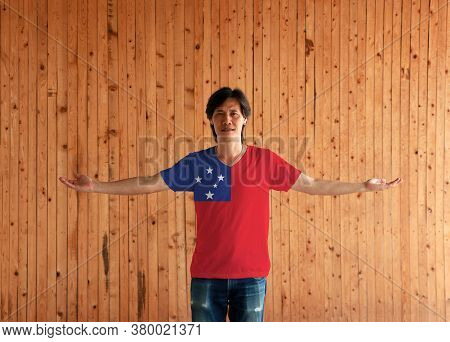 Man Wearing Samoa Flag Color Shirt And Standing With Arms Wide Open On The Wooden Wall Background, A