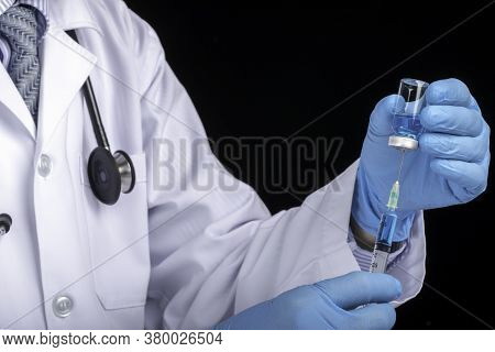 A Doctor In White Coat Drawing Clear Light Blue Liquid From A Vial Into A Syringe. Medication Or Vac