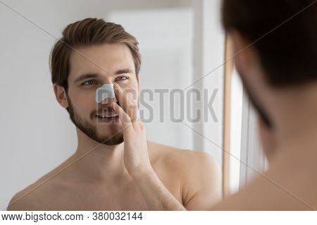 Mirror Reflection Smiling Man Applying Anti Blackhead Mask On Nose