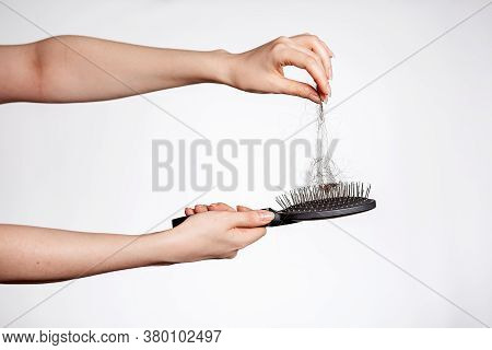 Females Hands Clean The Comb From Fallen Hair. Close Up. White Background. Concept Of Hair Loss, Bal