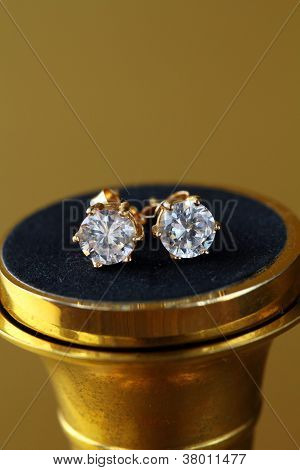 perno di orecchini in oro con diamanti su sfondo oro