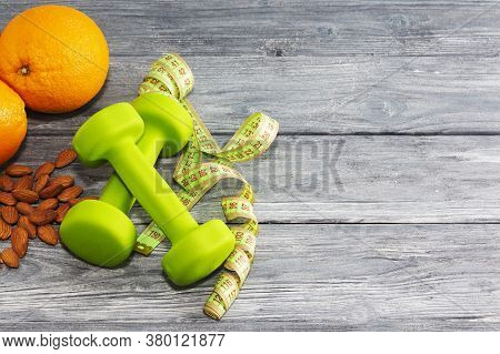Lots Of Oranges, Dumbbells, Measuring Tape On A Wooden Textured Background. Fitness, Sports Nutritio
