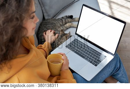 Young Hispanic Latin Teen Girl Student Relax Sit On Sofa With Cat Holding Laptop Looking At Mock Up 