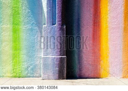 Rainbow Colored Wall Of Building Along Sidewalk.