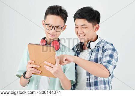 Excited Asian Teenage Boys Discussing New Application On Tablet Computer