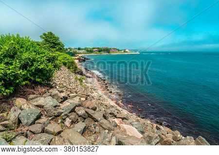 Blue Beach With Rocks And Houses On The Shore With Copy Space Fo