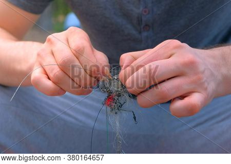 Man Untangles A Fishing Line And Hooks Preparing To Fishing, Hands Closeup. Fishing Equipment And To